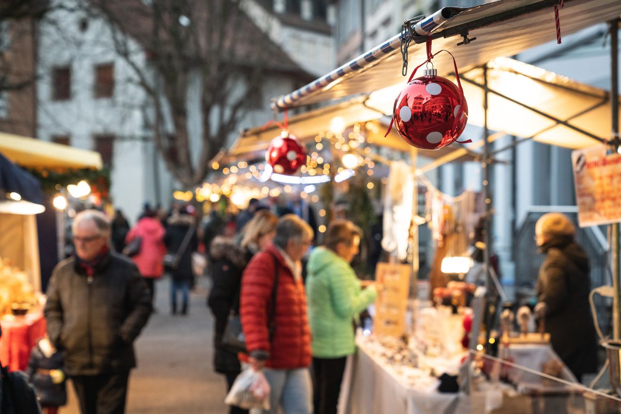 Market stalls with red baubles and fairy lights in Baden's city centre at dusk