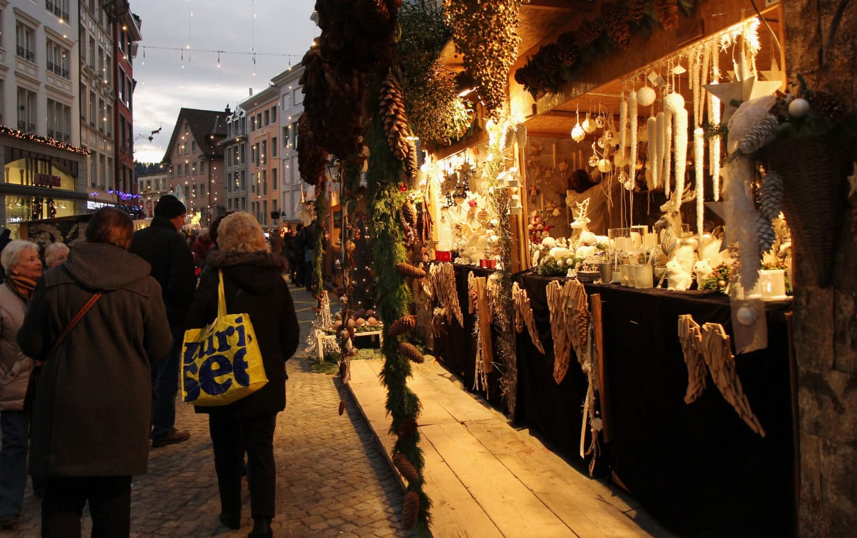 Illuminated stalls with Christmas decorations on Hauptstrasse at dusk